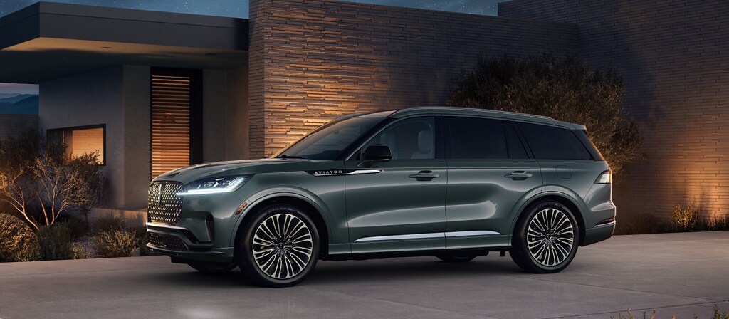 A 2027 Lincoln Aviator® Black Label® is parked next to a modern home at night
