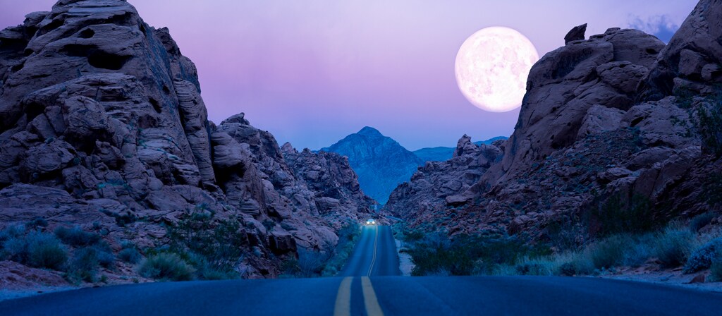 The moon hangs low over a highway in the desert southwest