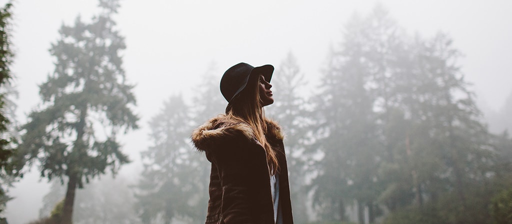 A woman walks through the forest following the conclusion of a rain storm