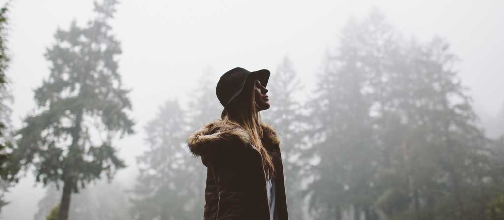 A woman walks through the forest following the conclusion of a rain storm