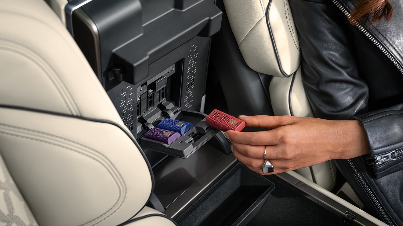 Close-up of a hand inserting a Lincoln Digital Scent cartridge into a slot inside the center console.