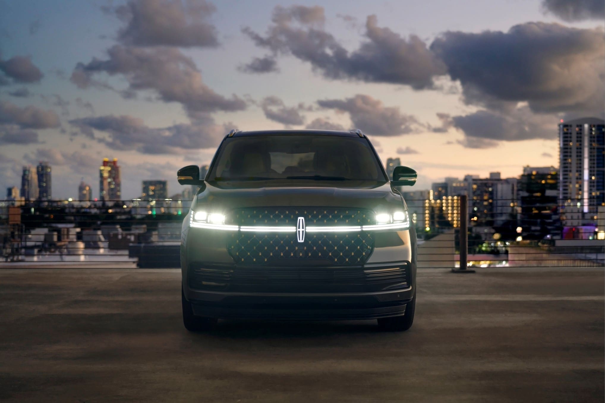 2025 Lincoln Black Label Navigator parked with a view of the city skyline at night in the background.