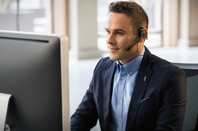A Lincoln customer service assistant is shown seated at a computer while wearing a headset