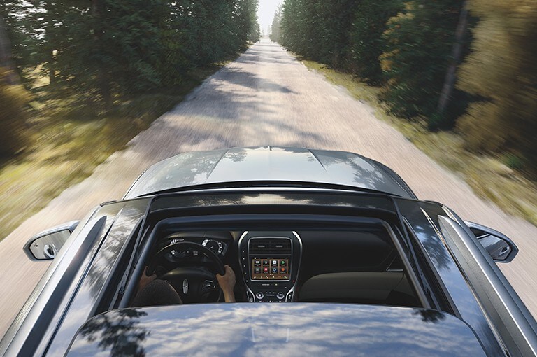 Lincoln owner driving through a country road with retractable roof open