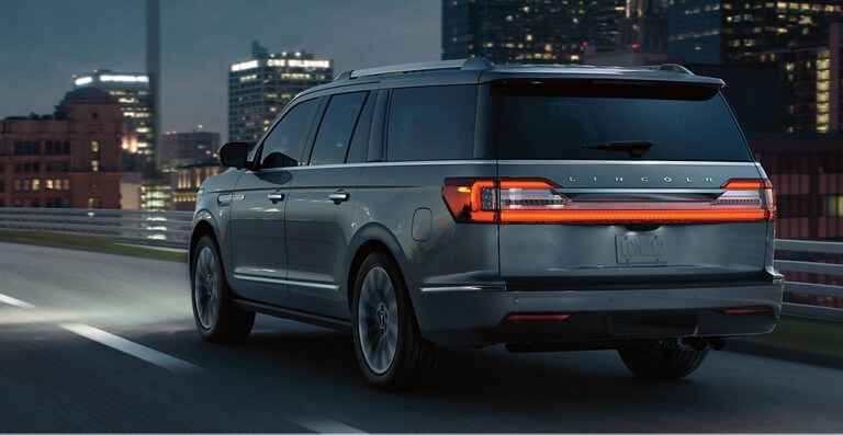 Lincoln Navigator driving down a city highway at night which demonstrates Post Collision Braking