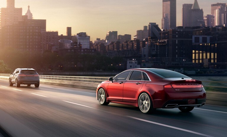 A red Lincoln M K Z in a city highway keeping a safe distance by using the Distance Alert Indication feature