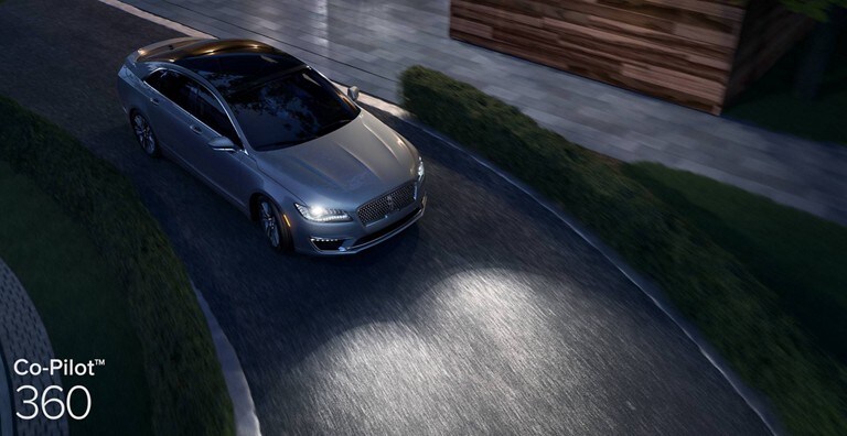 A grey Lincoln sedan on a road at night demonstrating the Auto High Beam Headlamps which is part of Co Pilot 3 60