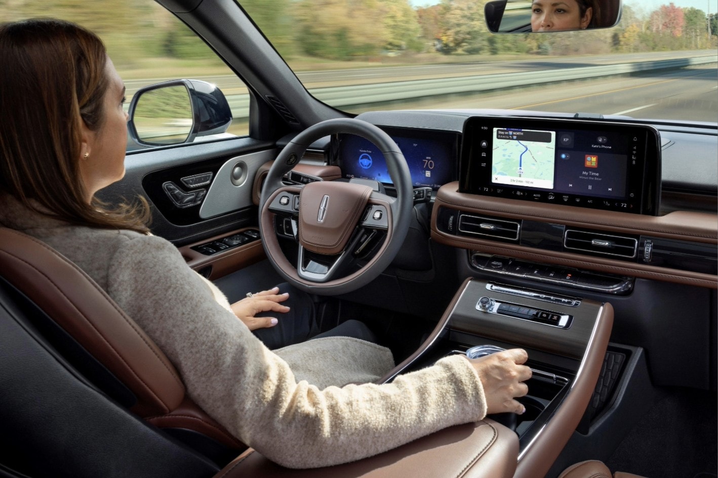 A woman in the driver seat of a Lincoln Nautilus relaxes with hands- free driving technology engaged