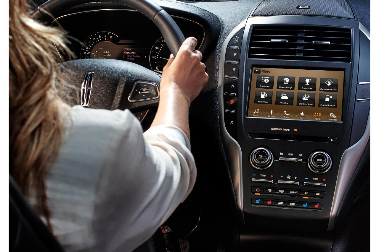 A woman drives a Lincoln, using SYNC 3 to effortlessly find her destination.