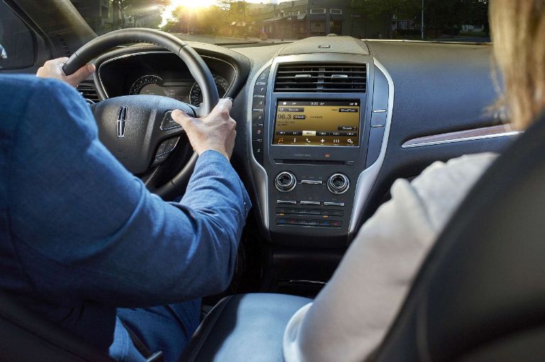 A couple sit in the front of a Lincoln, ready to use SYNC 3 voice recognition.