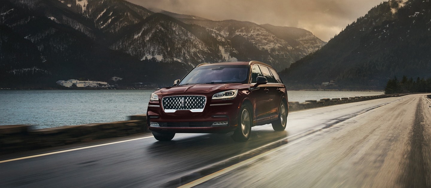A 2023 Lincoln Aviator® is shown being driven along a road in a breathtaking river valley