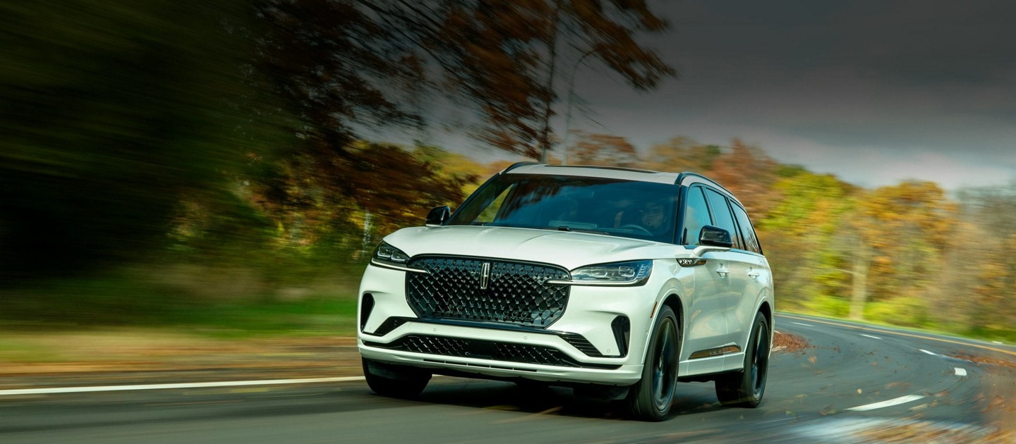 A 2025 Lincoln Aviator Reserve driving down a winding road lined with trees