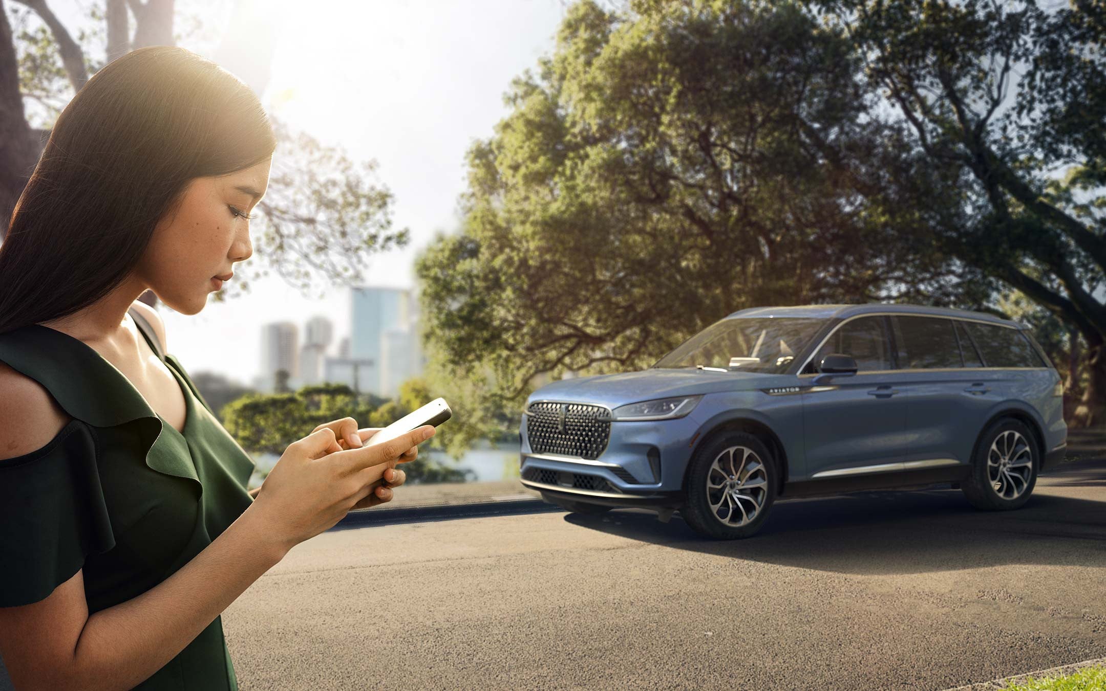 A person holds a smartphone as they approach a Lincoln vehicle