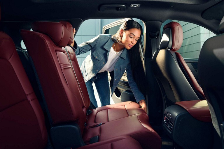 A woman slides the Second-Row seat forward to create more cargo space