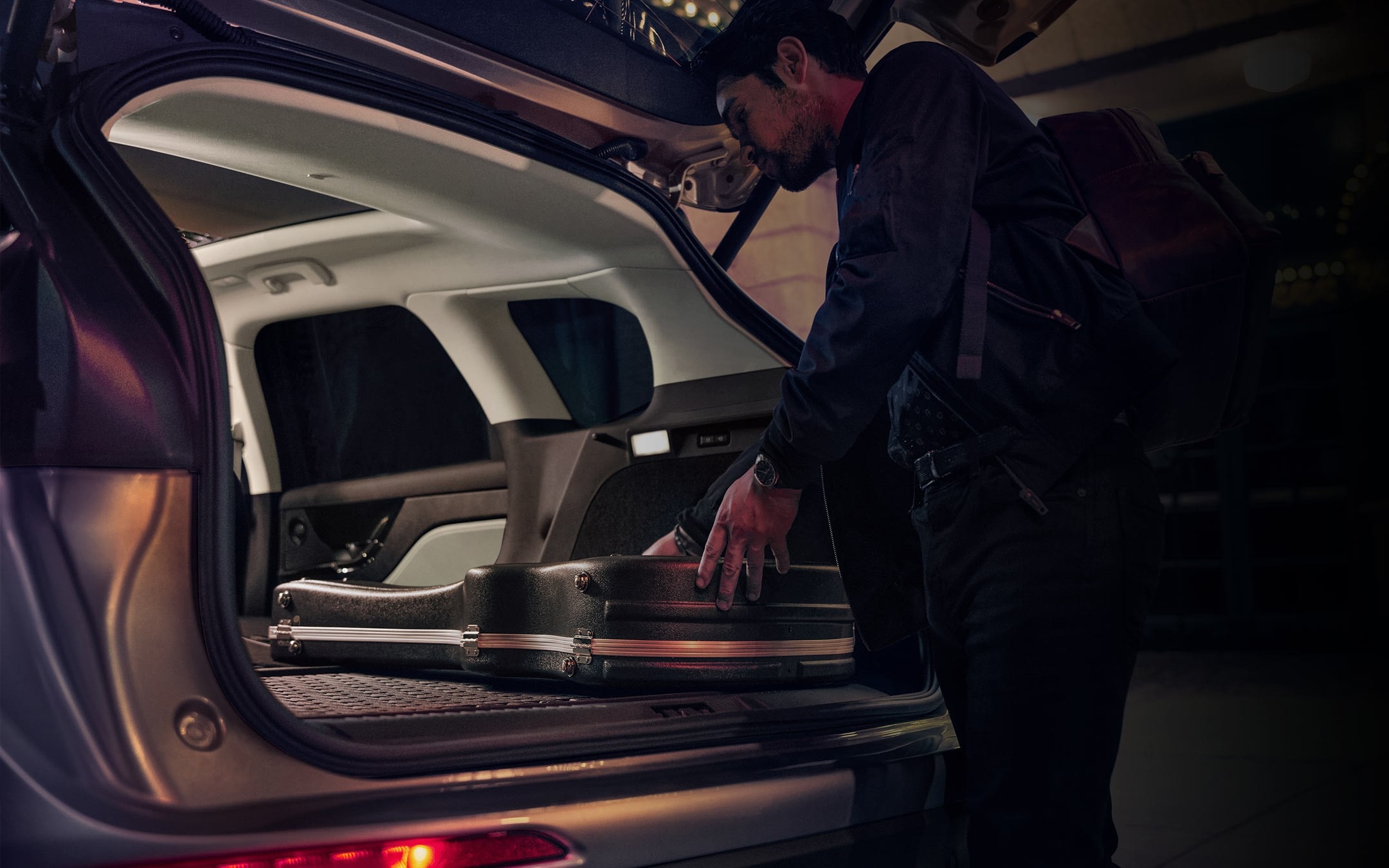 A musician loads musical equipment in the rear cargo area of a 2026 Lincoln Corsair