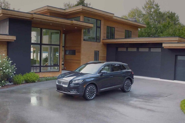 A 2023 Lincoln Nautilus SUV is parked in the driveway of a modern home