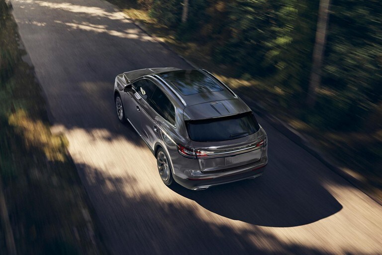 A 2023 Lincoln Nautilus is being driven on a tree-lined road