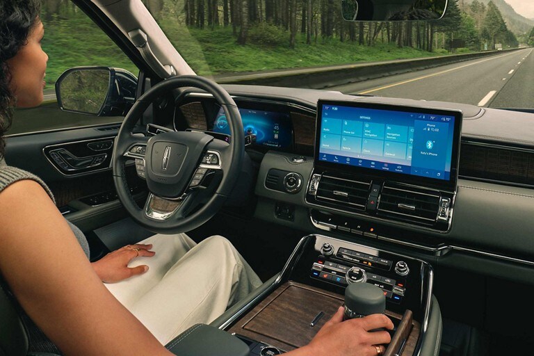 Through the windshield of a 2023 Lincoln Navigator® SUV there’s a woman sitting in the driver’s seat