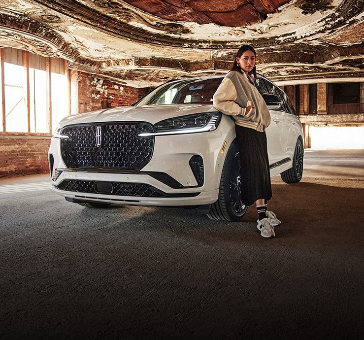 A woman standing infront of a Lincoln vehicle.