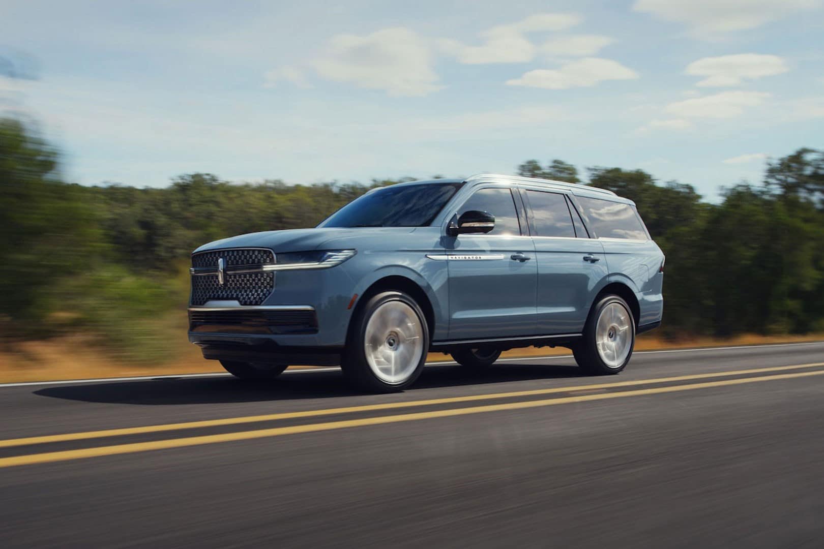 A 2025 Lincoln Navigator is shown being driven along a road.