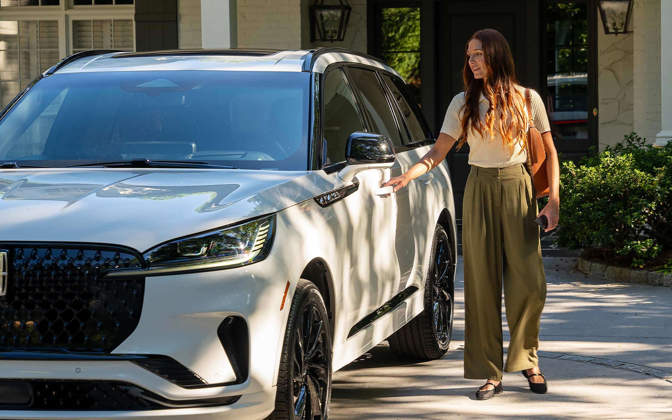 A person approaches a 2025 Lincoln Aviator® while holding a mobile phone