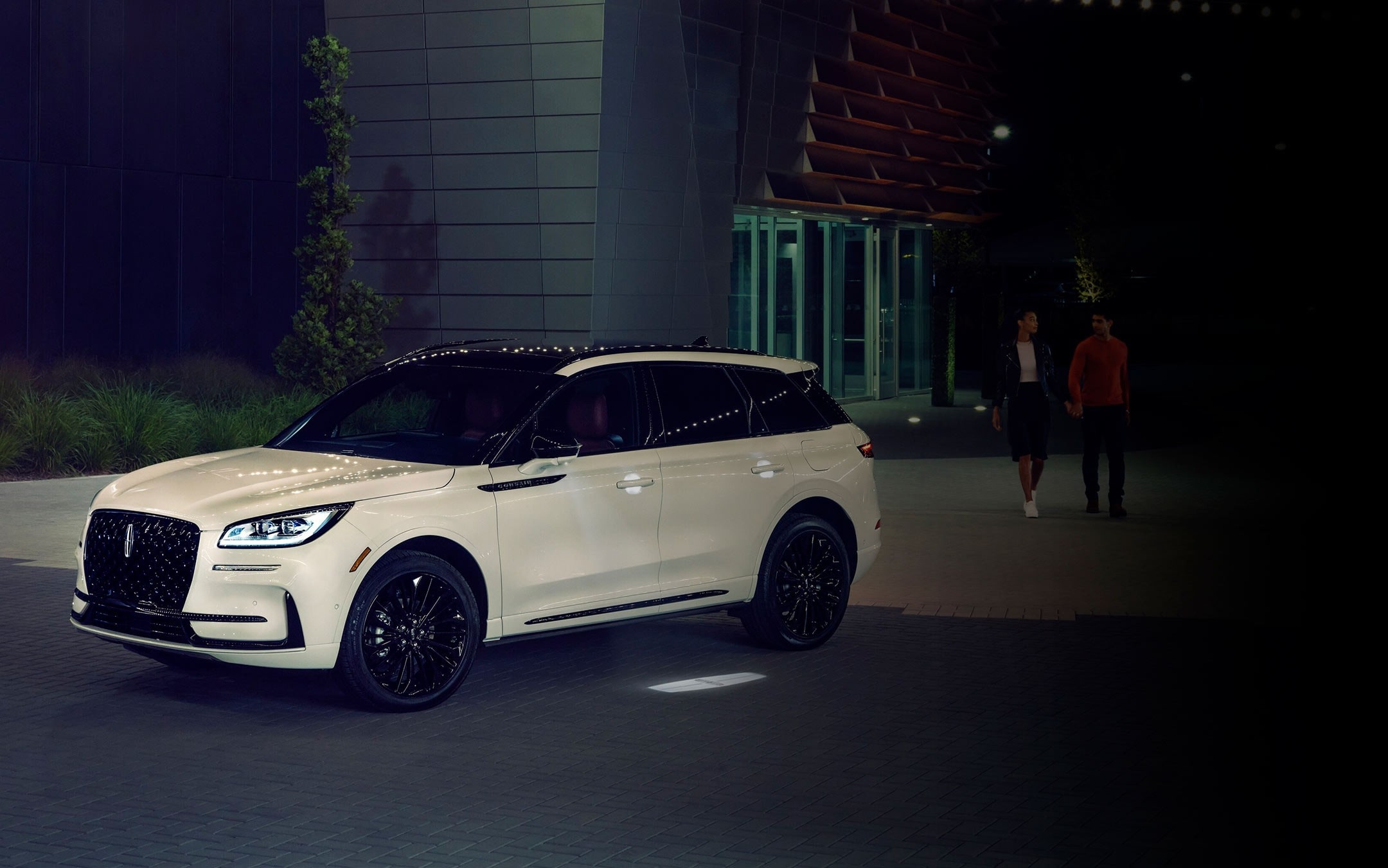 A couple approaches a 2025 Lincoln Corsair as the Lincoln Embrace illumination guides the way