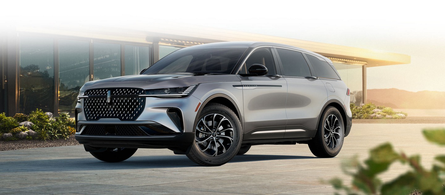 A 2025 Lincoln Nautilus Premiere in Lustrous Grey is parked in a driveway at sunset