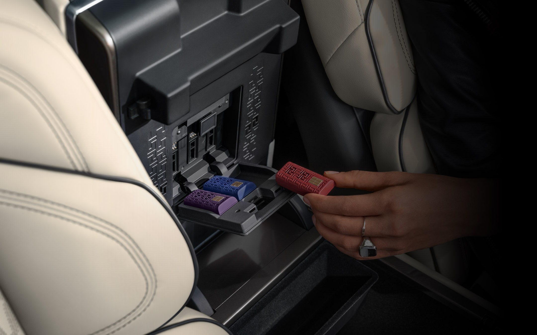 A hand inserts a Digital Scent cartridge in the opened storage bin of a 2026 Lincoln Nautilus