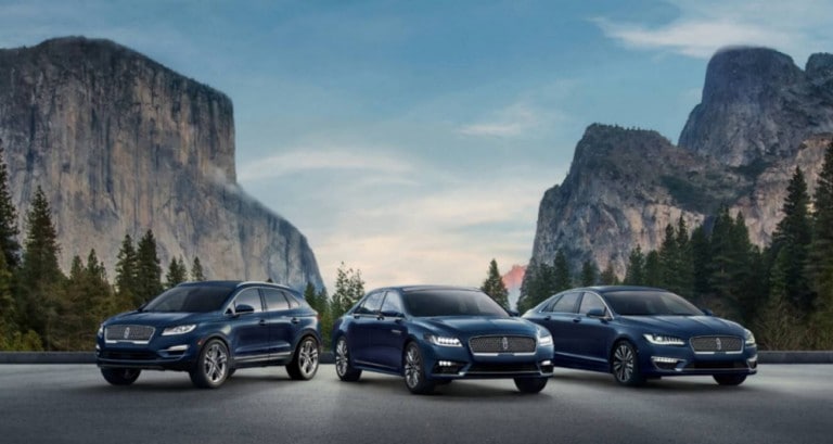 Various blue 2018 and 2019 Lincoln vehicles parked in front of mountains with blue sky