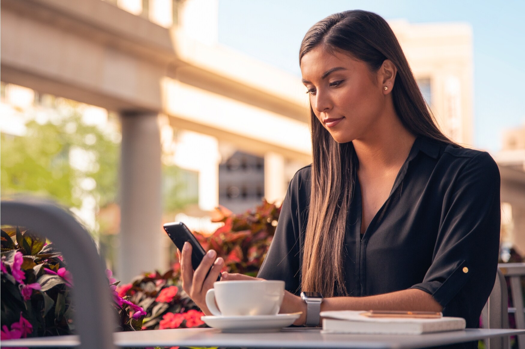 A woman is shown looking at her mobile device outdoors.