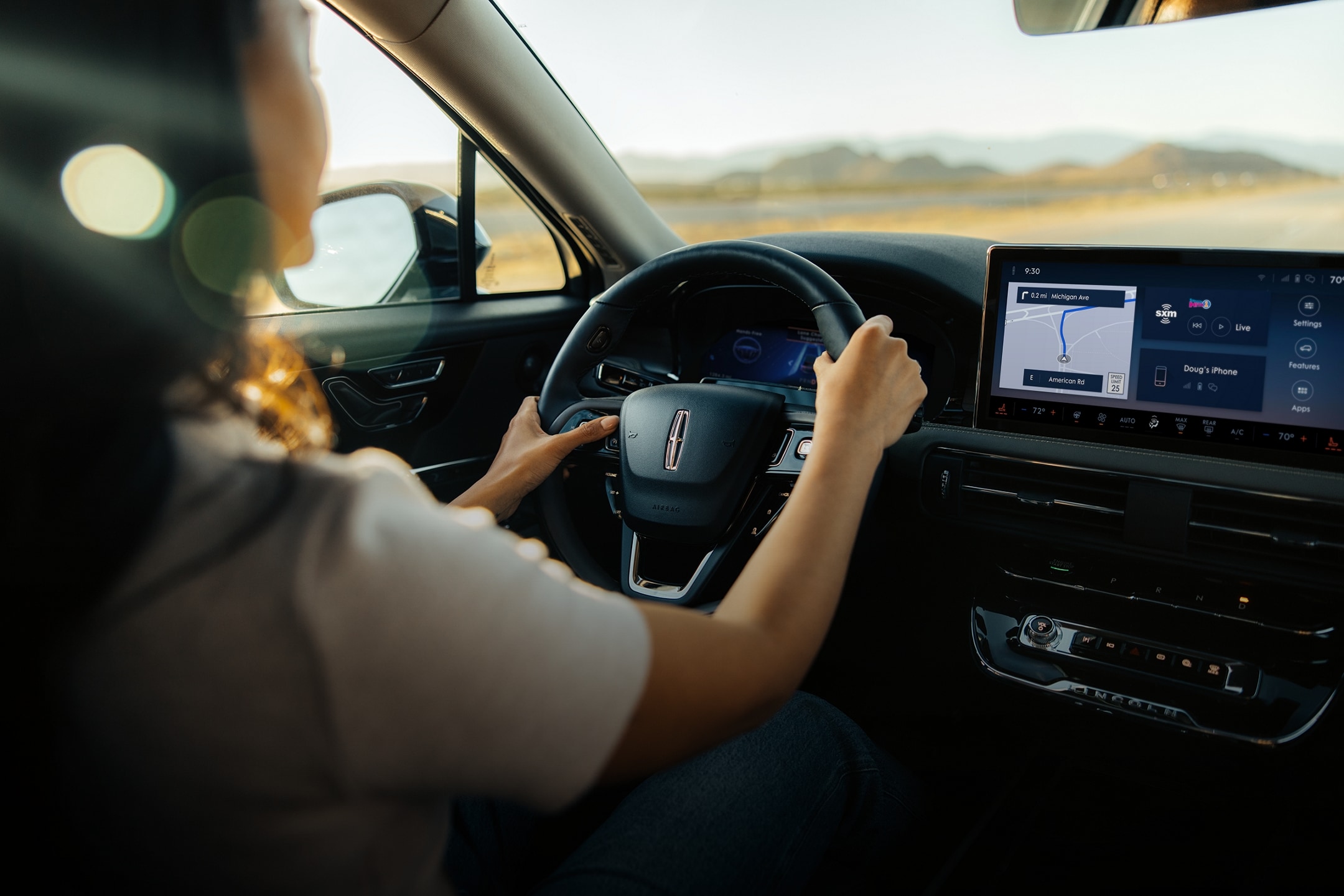 A woman is shown driving a Lincoln vehicle on a desert road with a map on the center-stack display.