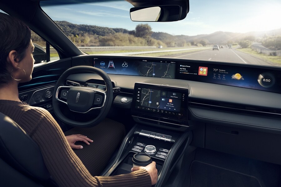 A woman is shown in the driver’s seat of a Lincoln Nautilus® SUV touching the center-stack display.