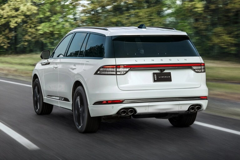 A 2026 Lincoln Aviator® SUV is shown driving on a forested road