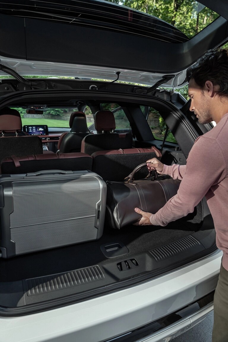 A person loads a leather bag into the rear cargo area of a 2026 Lincoln Aviator