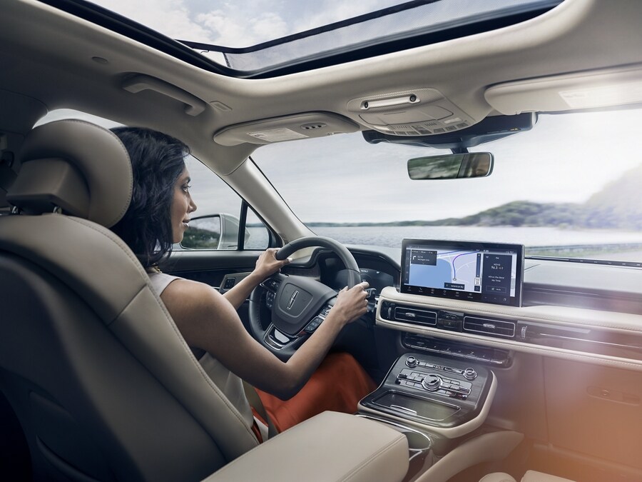 A person is shown driving a 2021 Lincoln Nautilus with the sync four navigation screen active