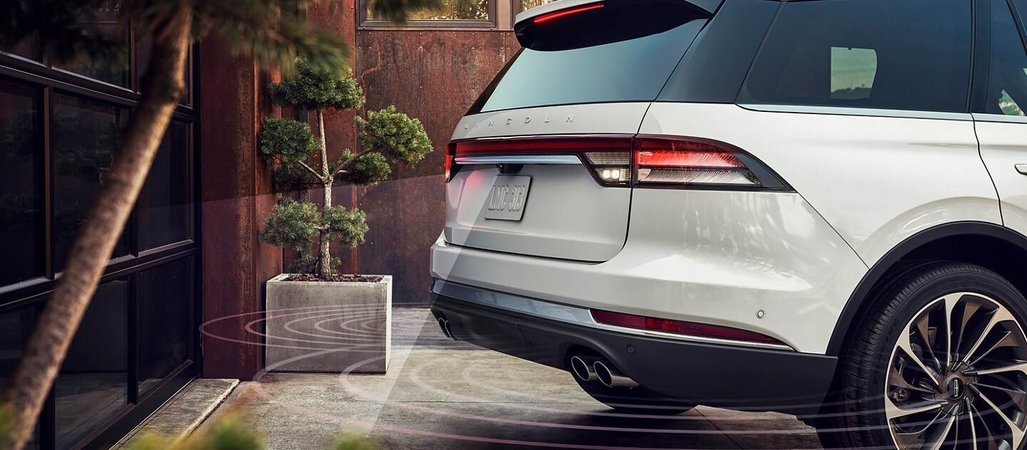 2023 Lincoln Aviator® backing up toward a garage and lines representing the sensor technology used to help prevent collision