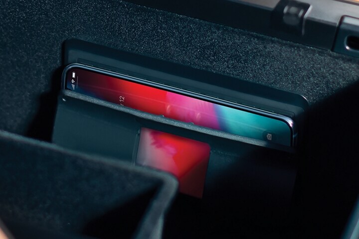 Front armrest storage bin of a 2023 Lincoln Aviator® with a phone in the wireless charger