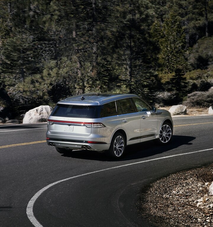 A 2023 Lincoln Aviator® is shown being driven through a sharp turn on a mountain road