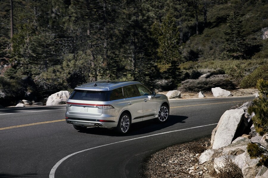 A 2023 Lincoln Aviator® being driven around a sharp turn on a mountain road