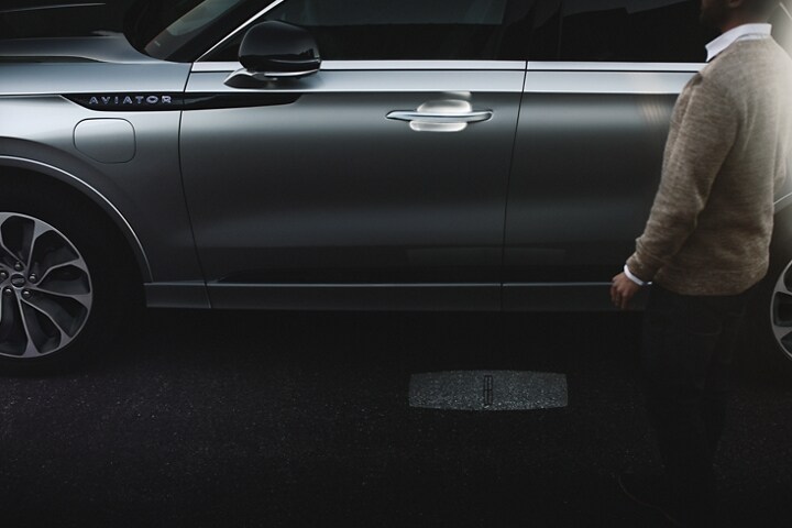 A person approaches a 2023 Lincoln Aviator® Grand Touring as the Lincoln Embrace welcome lighting illuminates