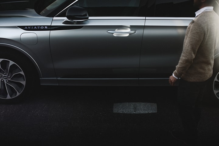 A person approaches a 2023 Lincoln Aviator® Grand Touring as the Lincoln Embrace welcome lighting illuminates