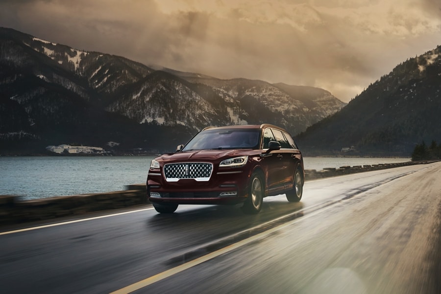 2023 Lincoln Aviator® Grand Touring in Burgundy Velvet being driven on a breathtaking river valley road