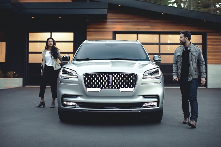 Couple leaving a 2023 Lincoln Aviator® Grand Touring model in the driveway of a modern home