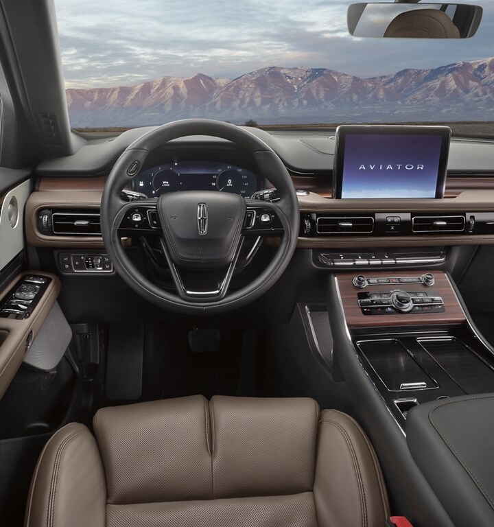 The steering wheel of a 2023 Lincoln Aviator® is featured with snow-capped mountains shown through the windshield