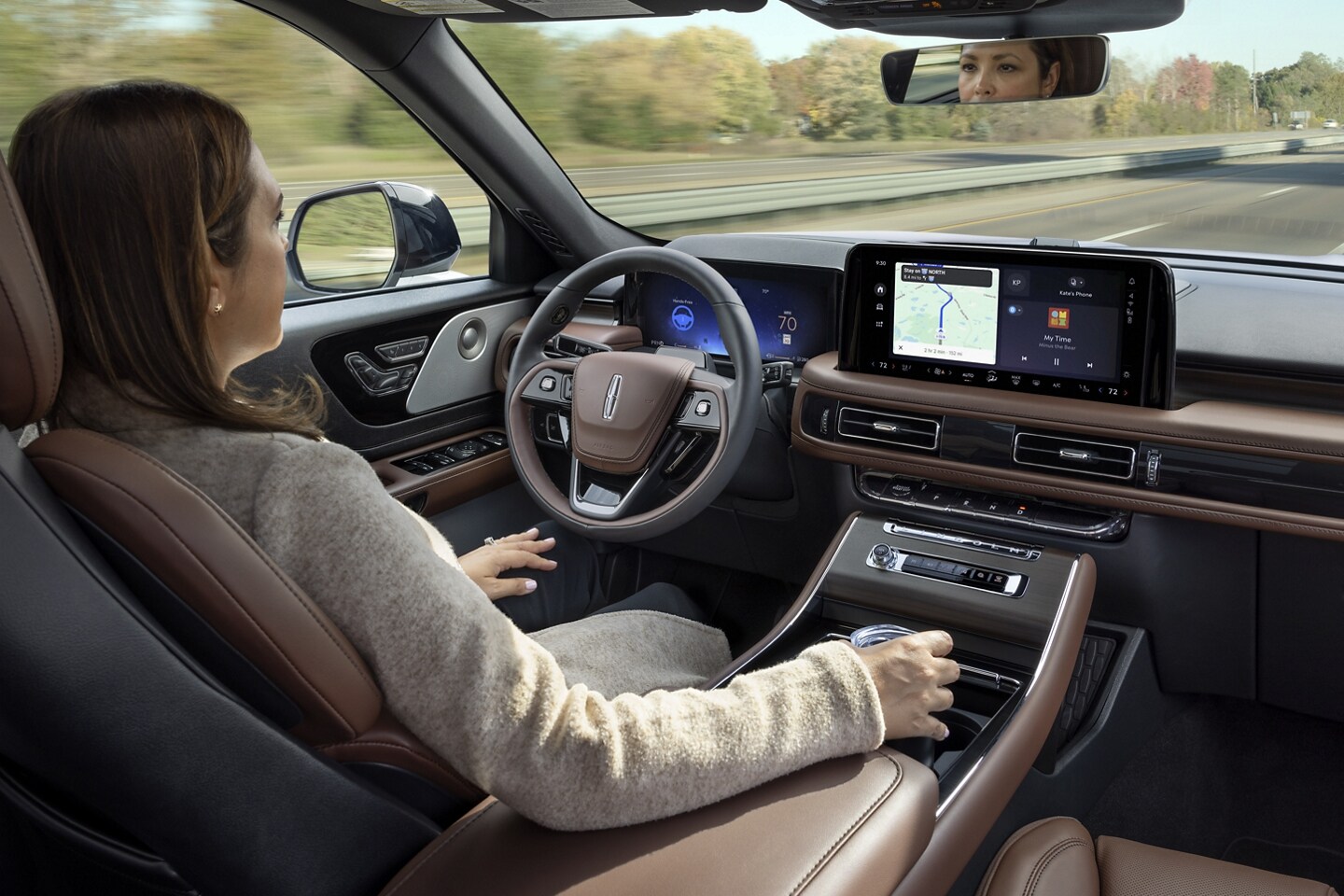 A 2025 Lincoln Aviator is being driven hands-free on a highway near a forest