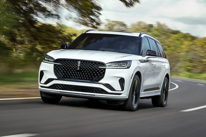 A 2025 Lincoln Aviator is shown driving on a forested road