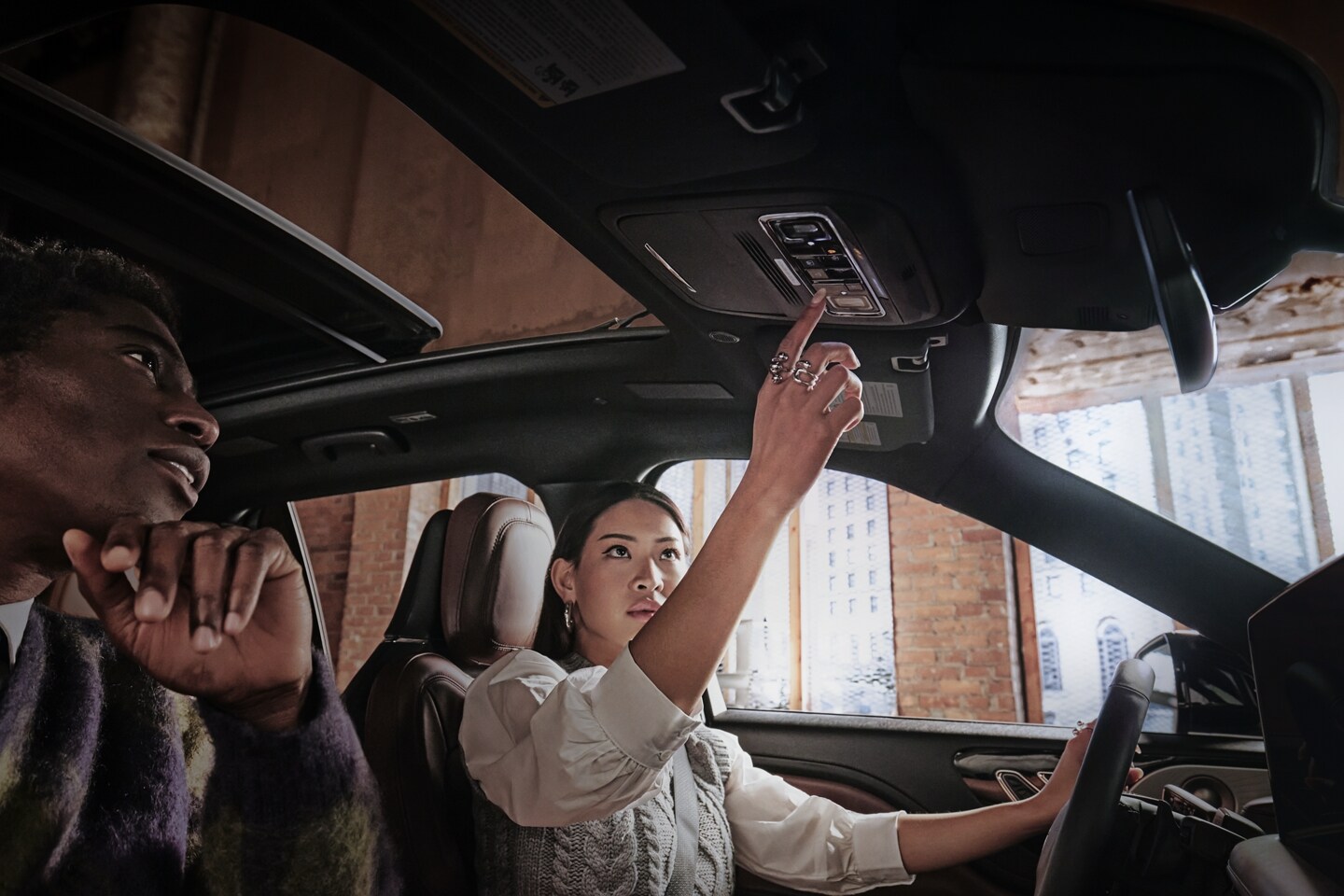 A woman is operating the panoramic Vista Roof® of a 2025 Lincoln Aviator