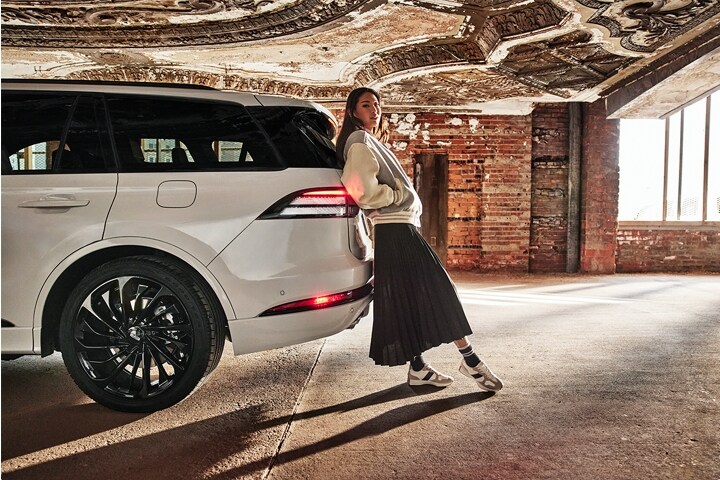 A woman leaning against the back of the 2025 Lincoln Aviator.
