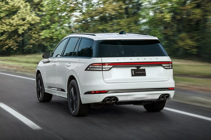 A 2025 Lincoln Aviator is shown driving on a forested road
