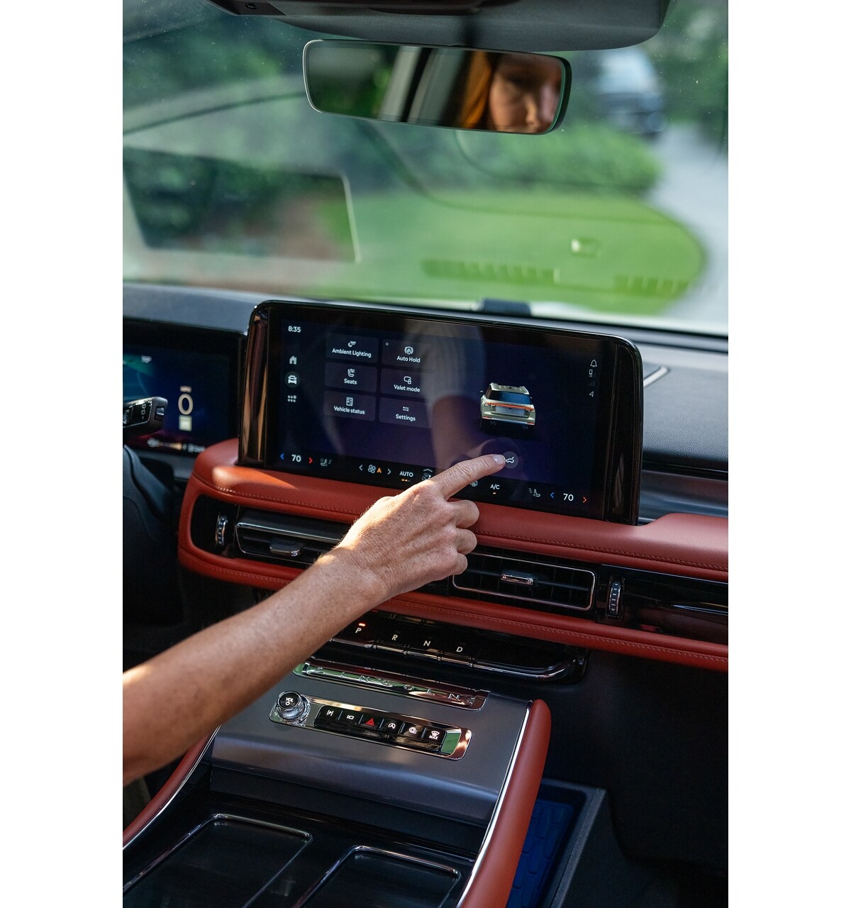 A person interacts with the center touchscreen to close the rear liftgate